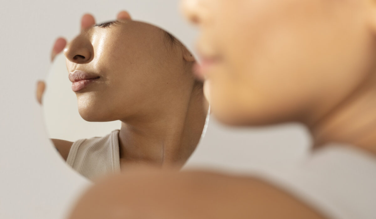 Resultado dos benefícios do Sculptra na pele evidenciado por mulher admirando seu reflexo no espelho