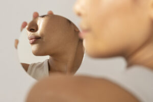 Resultado dos benefícios do Sculptra na pele evidenciado por mulher admirando seu reflexo no espelho